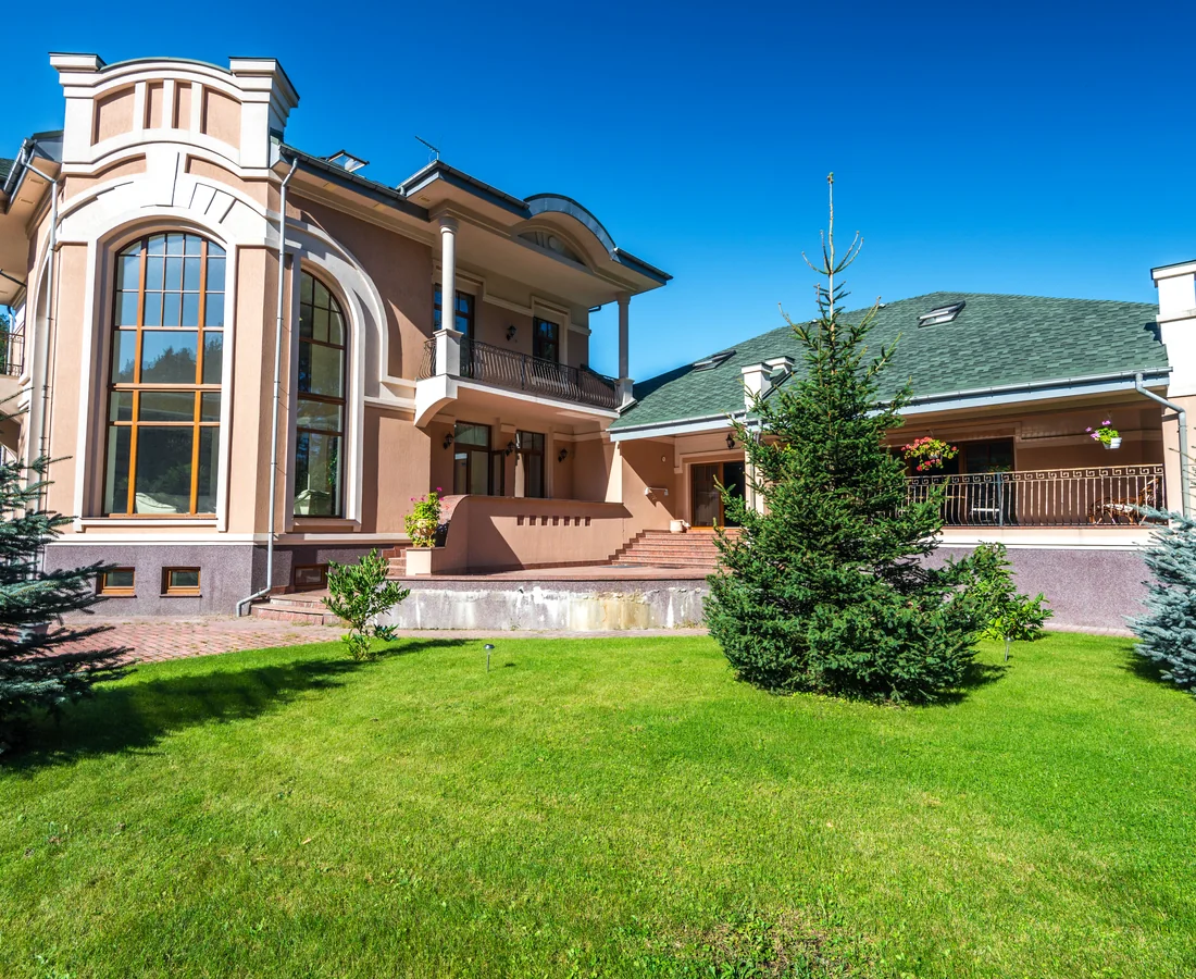 Großzügige Villa mit hohen Fenstern, gegliederter Fassade, Terrasse und gepflegtem Garten