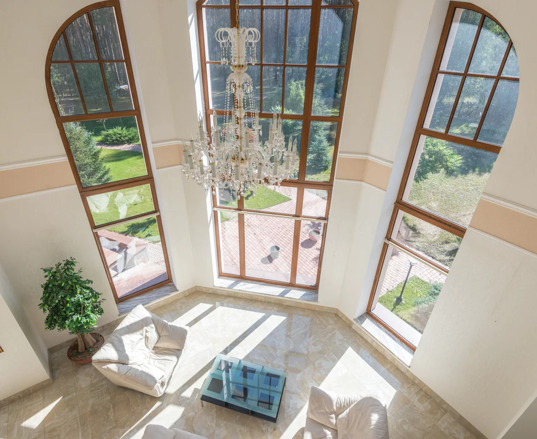 Sehr heller hoher Wohnraum mit großen Fensterachsen, Sitzbereich und Blick in den Garten